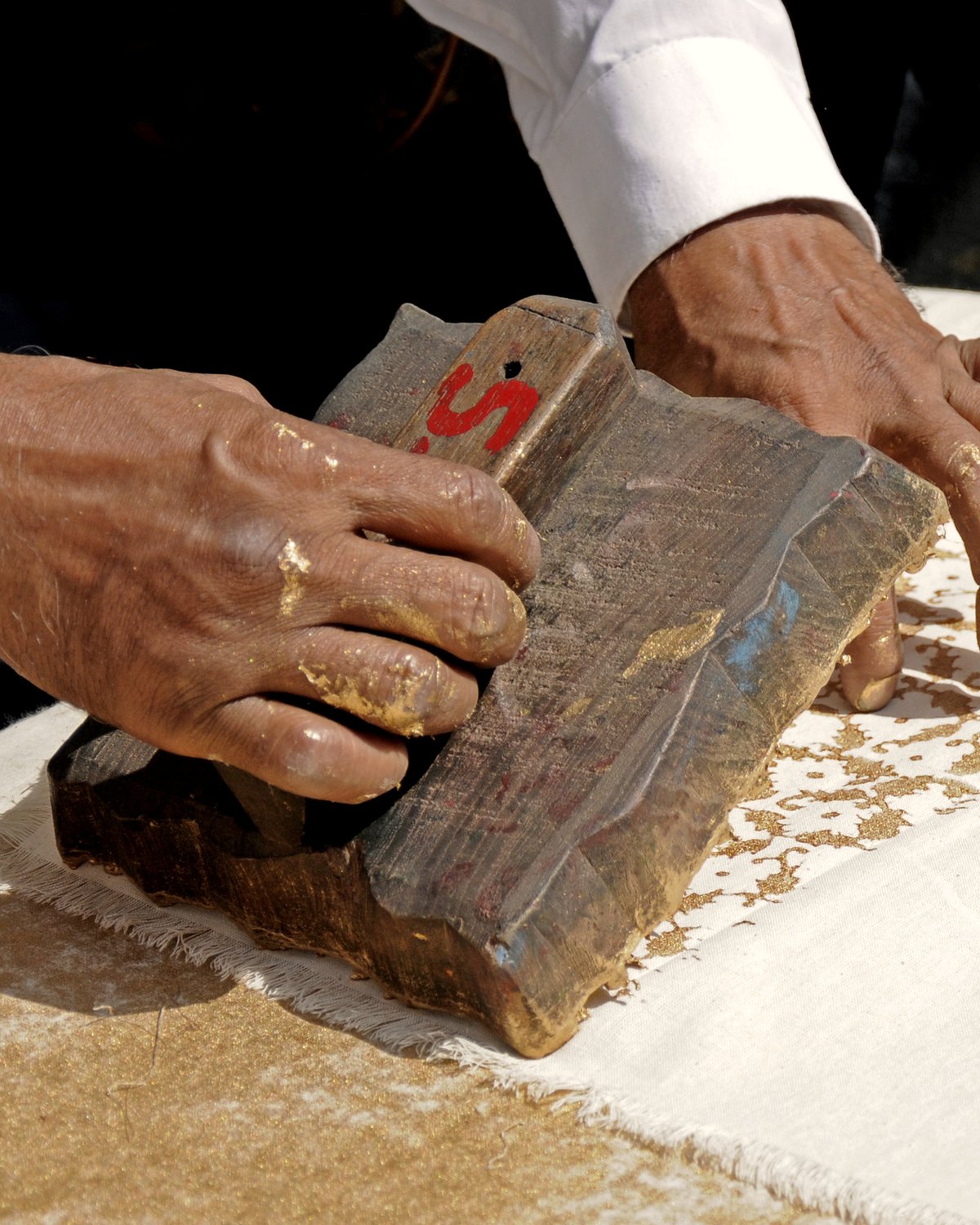 A block printer pressing a carved teak block onto cloth